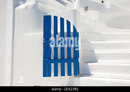 Blaues Holztor vor dem Hintergrund einer weißen Steinmauer und einer weißen Steintreppe. Santorini Griechenland. Stockfoto