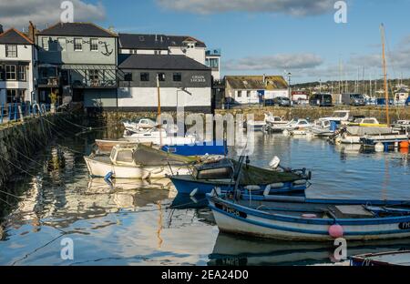 Custom House Quay und Chain locker von Falmouth, über das Wasser und Boote bei Flut mit Reflexionen in der Sonne gesehen Stockfoto