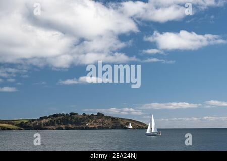 Weiße Segelyacht geht in Falmouth Bay vorbei am St Anthony's Head Leuchtturm bei einer frischen Brise und schönem bewölkten Himmel. Gefühl der Freiheit. Stockfoto