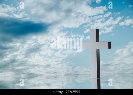 Ein weißes Kreuz gegen den blau bewölkten Himmel. Stockfoto