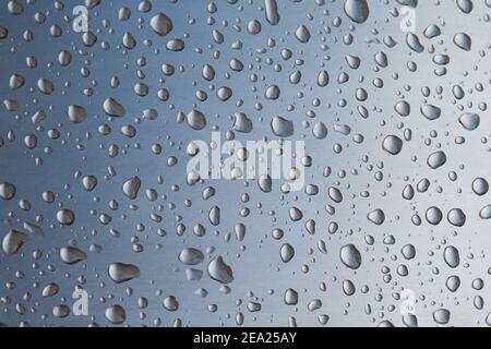 Foto Textur Tropfen Wasser auf einem Metallstahl. Makro viele Tropfen Wasser verschiedener Größen auf einem grauen Hintergrund. Die linke Ecke ist abgedunkelt. Getönte i Stockfoto