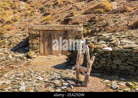 Ein Holztor mit Vorhängeschloss zu einem Ausguß am Hang. Folegandros Island, Griechenland. Stockfoto