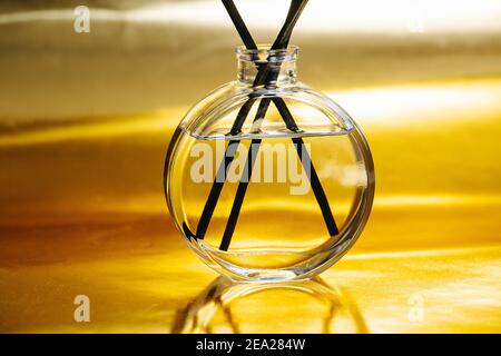 Nahaufnahme von Duftstäbchen und Flasche mit ätherischem Öl auf Eine gelbe Metalloberfläche Stockfoto