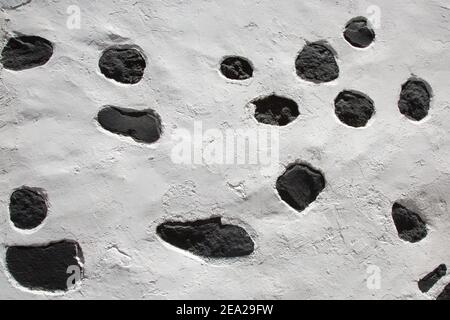 Weiße Steinmauer mit schwarzen vulkanischen Flecken Stockfoto