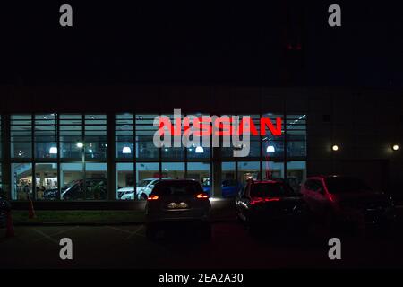 MOSKAU, RUSSLAND - NOVEMBER 24 2019: Neon-rotes Schild Nissan Night auf der Autoworld Auto Krylatskoye. In den dunklen Fenstern sind sichtbare Silhouetten von Autos Stockfoto