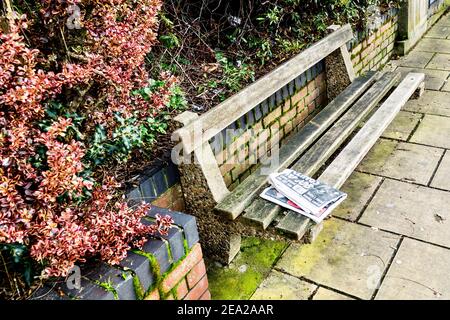 Eine gebrauchte Boulevardzeitung faltete sich in zwei Hälften und hinterließ eine Holzbank auf der Hauptstraße. London. VEREINIGTES KÖNIGREICH. Stockfoto