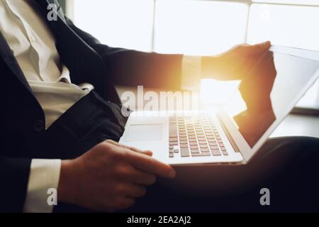 Businessman arbeitet auf dem Sofa mit seinem Laptop. Er ist im Smart Working Stockfoto