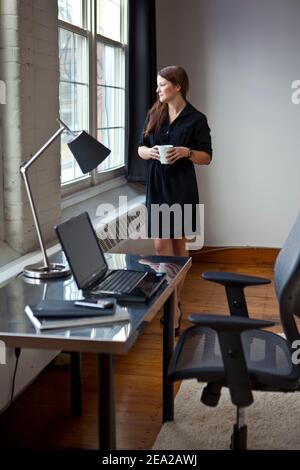 Eine junge Geschäftsfrau denkt während einer Kaffeepause bei der Arbeit nach. Stockfoto