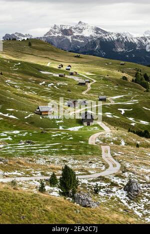 Auf den Wiesen der Petzer Alp unter dem Peitlerkofel im Herbst, Dolomiten, Südtirol, Italien liegen Holzhütten und Schnee Stockfoto