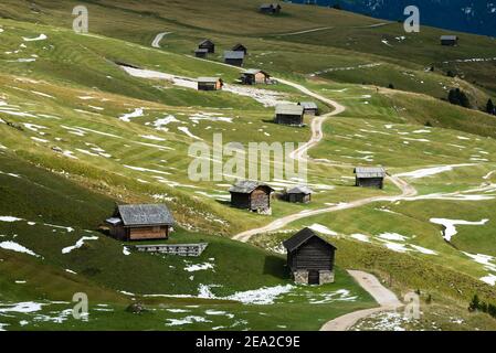 Auf den Wiesen der Petzer Alp unter dem Peitlerkofel im Herbst, Dolomiten, Südtirol, Italien liegen Holzhütten und Schnee Stockfoto