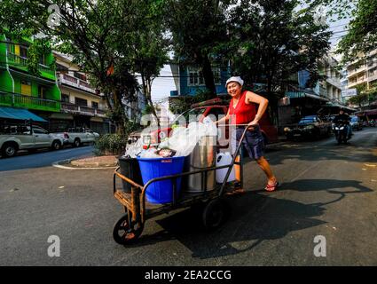 Eine Frau schiebt einen Trolley entlang der Straße in der Chinatown Gegend von Bangkok, Thailand Stockfoto