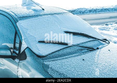 Die gefrostete Windschutzscheibe eines Autos an einem Wintermorgen. Eine Schutzmatte schützt vor Frost an der Windschutzscheibe. Stockfoto