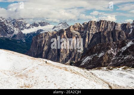 Wanderer auf einem verschneiten Berg vor herbstlicher Dolomitenlandschaft mit den Felswänden der Gipfel Puez-Geisler und Fanes-Sennes-Prags, Südtirol, Italien Stockfoto