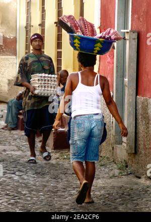 Straßenszene in Porto Grande, Sao Vincente, Kapverdische Inseln. Frauen tragen Fischlieferung auf ihrem Kopf. Farbenfrohe, gepflasterte Straßen. Stockfoto