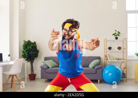 Fröhlicher Trainer schaut und zeigt auf Kamera zu motivieren, Sport zu beginnen. Stockfoto