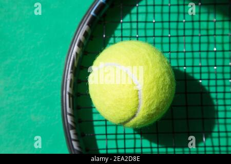 Nahaufnahme Tennisball auf Schläger und grünem Hintergrund. Konzept im Tennis. Stockfoto