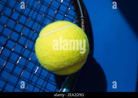 Nahaufnahme Tennisball auf blauem Hintergrund. Schwarzer Text COVID-19 hinzugefügt. Coronavirus-Epidemie Konzept ist im Tennis. Stockfoto