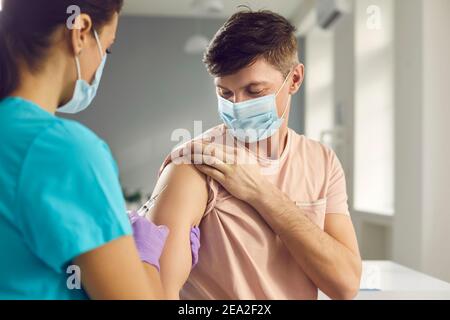 Weibliche medizinische Arbeiter impfen Mann Patient in Arm Stockfoto