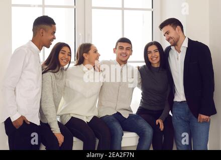 Gruppe von glücklichen jungen Freunden, Kollegen oder Studenten versammelten sich am Fenster alle zusammen Stockfoto