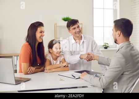 Immobilienmakler Händeschütteln mit glücklichen Vater sitzen mit Frau und Tochter nach erfolgreichem Deal Stockfoto