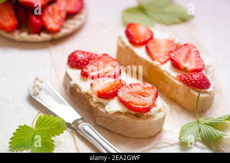 Erdbeeren Sandwiches mit Frischkäse und auf Papier, leichter Hintergrund Stockfoto