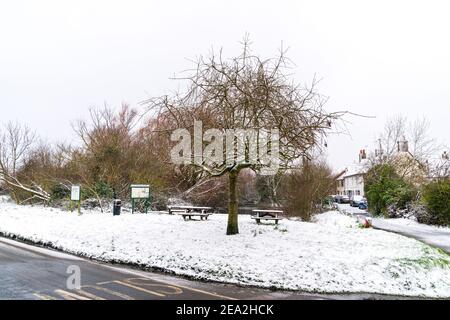 Broomfield, Herne Bay Ententeich. Blick über das kleine Dorf Grün mit dem Ententeich im Hintergrund und einer schmalen Straße, die an malerischen kleinen Häusern vorbei führt. Vordergrund ist ein Baum und Bänke und Tische. Stockfoto