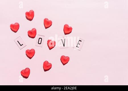 Banner.das Wort Liebe.Schwarze Buchstaben Liebe mit roten Herzen.auf rosa Hintergrund.Valentinstag. Liebevolle, positive Emotionen. Gefühle Hintergrund. Exklusiv Stockfoto