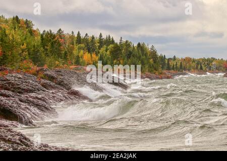 Große Wellen am felsigen Ufer des Lake Superior entlang des Herbstes Wald Stockfoto