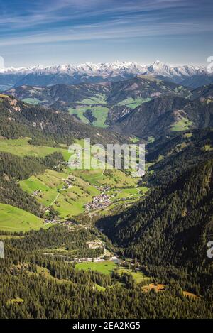 Das Campilltal und Dorf in den Dolomiten vor dem Panorama des verschneiten Alpenhauptkamms im Herbst bei Sonnenschein, Südtirol, Italien, Europa Stockfoto