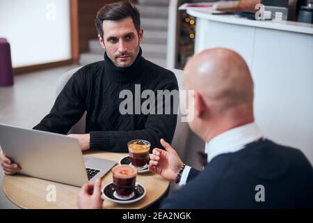 Junger Geschäftsmann im Gespräch mit Partner in informeller Atmosphäre Stockfoto