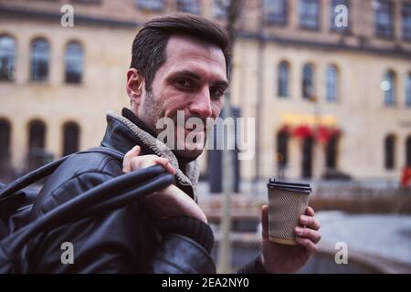 Glücklicher junger Mann, der Kaffee auf der Straße trinkt Stockfoto