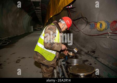 (210207) -- URUMQI, 7. Februar 2021 (Xinhua) -- EIN Arbeiter hat eine Mahlzeit auf der Baustelle des Tianshan Shengli Tunnels in der Autonomen Region Xinjiang Uygur im Nordwesten Chinas, 4. Februar 2021. Der Tianshan Shengli-Tunnel ist mit einer Gesamtlänge von rund 22 Kilometern derzeit der längste im Bau befindliche Autobahntunnel in China. Der 2020 begonnene Tunnel, ein sechsjähriges Projekt auf der Urumqi-Yuli-Autobahn, durchläuft eine kalte und hochgelegene Zone mit rauem Klima und geologischem Zustand. Nach Fertigstellung und für den Verkehr geöffnet, wird es sicherer und bequemer Reisen für die Passagiere und Stockfoto