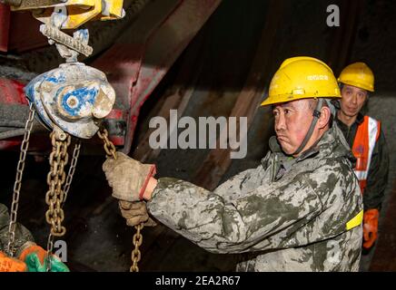 (210207) -- URUMQI, 7. Februar 2021 (Xinhua) -- Arbeiter sind auf der Baustelle des Tianshan Shengli Tunnels in der Autonomen Region Xinjiang Uygur im Nordwesten Chinas beschäftigt, 4. Februar 2021. Der Tianshan Shengli-Tunnel ist mit einer Gesamtlänge von rund 22 Kilometern derzeit der längste im Bau befindliche Autobahntunnel in China. Der 2020 begonnene Tunnel, ein sechsjähriges Projekt auf der Urumqi-Yuli-Autobahn, durchläuft eine kalte und hochgelegene Zone mit rauem Klima und geologischem Zustand. Nach der Fertigstellung und für den Verkehr geöffnet, wird es sicherer und bequemer Reisen für die Passagiere und p Stockfoto