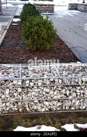 Trennung der Straße vom Parkgelände. Ein Fragment der Raumordnung mit der Verwendung von Gabionen. Winter. Stockfoto