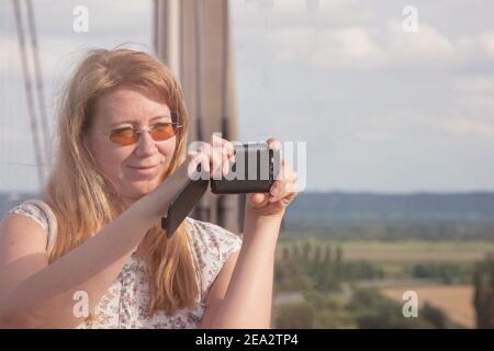 Attraktive blonde Frau Touristen macht Bilder auf Brücke Landschaft in frankreich. Frau mit Mobiltelefon. Stockfoto