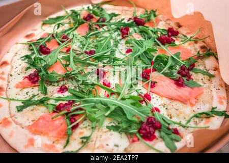 Köstliche frische und schmackhafte italienische Pizza mit Lachs, Rucola-Grüns und würziger Cranberry-Sauce. Schnelle und befriedigende Snack und Mittagessen Stockfoto