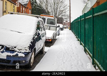 Auto auf der britischen Straße unter Winter Schnee fallen in geparkt england gb Stockfoto
