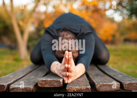 Frau tut Yoga Stretching im Freien mit Händen geklammert. Konzentrieren Sie sich auf die Hände berühren in Kinderpose, Balasana. Training in der Natur, gesundes Lifestyle-Konzept Stockfoto