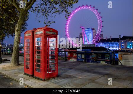 Das London Eye bei Nacht mit zwei roten Telefonzellen, London Stockfoto