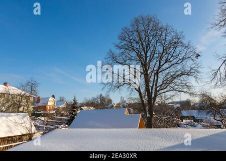 Dach mit Schnee auf einem Hintergrund aus Eiche an einem sonnigen Tag. Winterlandschaft ist in einer kleinen Stadt Zvenigorod in Russland Stockfoto