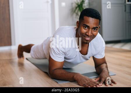 Nahaufnahme des afroamerikanischen Mannes, der während des Trainings in Plankenposition auf dem Boden trainiert. Stockfoto