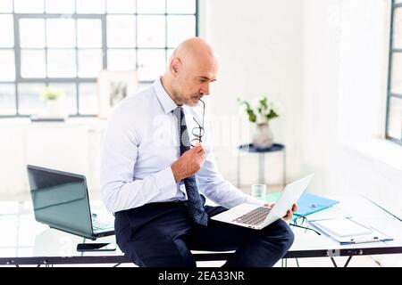 Porträtaufnahme eines Geschäftsmanns, der bei der Arbeit im Büro nachdenklich aussieht. Stockfoto