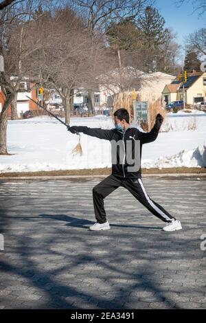 Ein junger chinesischer Amerikaner macht anmutig Tai Chi mit Schwertübungen im Kissena Park in Flushing, Queens, New York City. Stockfoto