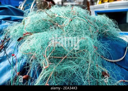 Hellblaue Fischernetze, verwickelt und stillgesetzt, auf dem Dock des Hafens. Zentrieren. Stockfoto