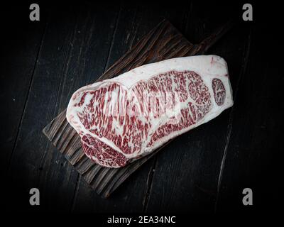 Stück Wagyu-Rindersteak. Rohes Rindersteak auf einem Holzhintergrund in einer Metzgerei. Japanisches Premium-Produkt. Stockfoto
