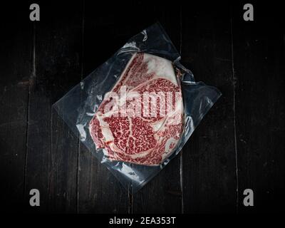 Vakuumverpacktes Stück Wagyu-Rindersteak. Rohes Rindersteak auf einem Holzhintergrund in einer Metzgerei. Japanisches Premium-Produkt. Stockfoto