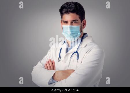 Nahaufnahme Studio-Porträt von männlichen Arzt trägt Gesichtsmaske, während auf isolierten Hintergrund stehen. Stockfoto