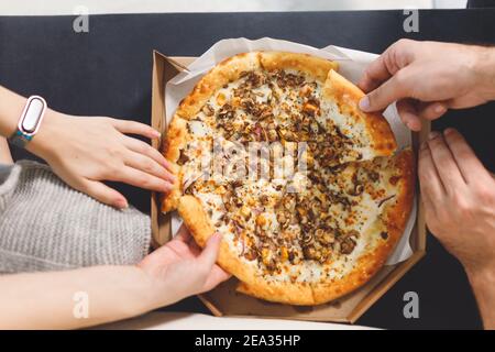 Junges Paar, das Pizza isst. Draufsicht Hände mit Pizza Stockfoto