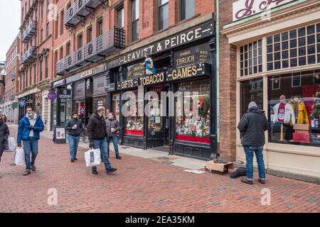 In Cambridge, in der Nähe der Harvard University, laufen die Käufer in Masken und Einkaufstaschen entlang einer belebten Straße. Stockfoto