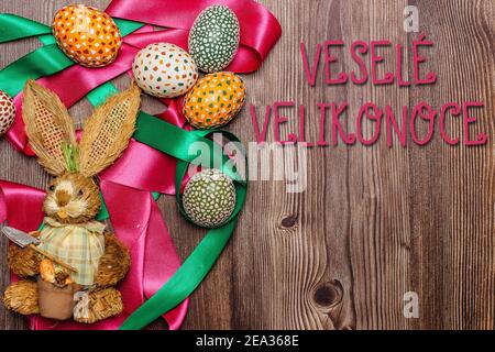 Frohe Ostern Textnachricht auf Tschechisch.Bunte Hand bemalt dekoriert Ostern Eier und Hase.Handgefertigte Ostereier auf Holztisch.Frühlingsdekoration Stockfoto